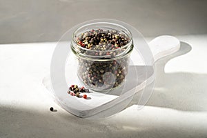 Mixed pepper corn. Black, red and white peppercorns in a glass jar.