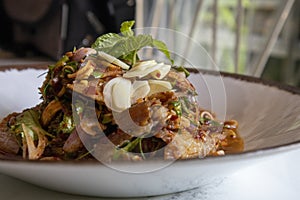 A mixed pork spicy salad on white plate.