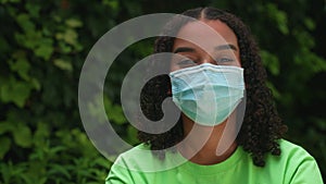 Mixed race African American girl biracial teenager young woman outside wearing a face mask during COVID-19