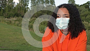 Mixed race African American girl biracial teenager young woman outside wearing a face mask during COVID-19 Coronavirus pandemic