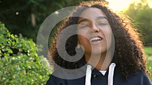 Mixed race African American girl teenager or young woman laughing, smiling and blowing a dandelio