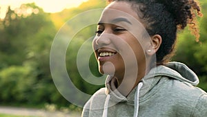 Mixed race African American girl teenager or young woman laughing, smiling and blowing a dandelion at sunset or sunrise