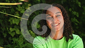 Mixed race African American girl teenager young woman looking sad then laughing and happy wearing a green t-shirt outside