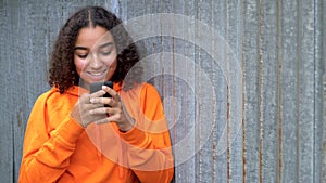 Mixed race African American girl teenager young woman using her smartphone or cell phone for social media