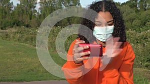 Mixed race African American girl teenager young woman wearing a face mask during COVID-19 Coronavirus pandemic using her smartphon