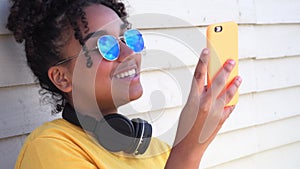 Mixed race African American girl young woman wearing sunglasses using cell phone for social media