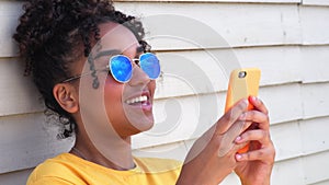 Mixed race African American girl young woman wearing sunglasses using her cell phone for social media