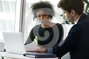 Multiracial colleagues analyzing financial report during meeting in office photo