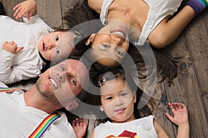 Mixed race Asian American family laying on floor looking at camera