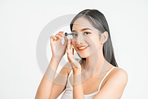 mixed race asian woman putting mascara on eyelashes on white background