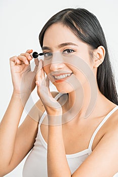 mixed race asian woman putting mascara on eyelashes on white background