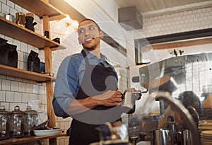 Mixed race barista steaming milk for coffee. Bistro worker frothing milk for a cup of coffee. Coffeeshop assistant