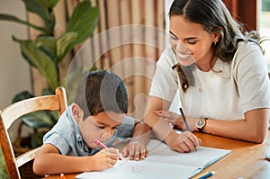 Mixed race boy learning and studying in homeschool with mom. Woman helping son with homework and assignments at home