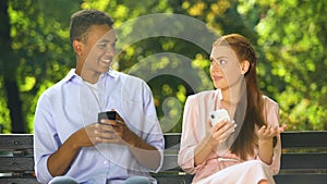 Mixed-race boy making compliment to gadget-addicted girl in social network, fail