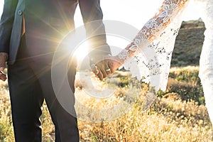 Mixed race bride and groom holding hands at sunset
