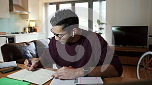 Mixed race business man working from home writing on note pad working from home office