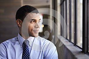 Mixed race businessman looking out of window, portrait