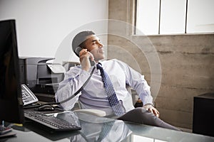 Mixed race businessman at an office desk using the phone