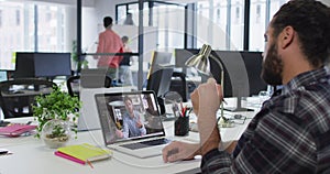 Mixed race businessman sitting at desk using laptop having video call with male colleague