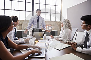 Mixed race businessman stands addressing team in a meeting