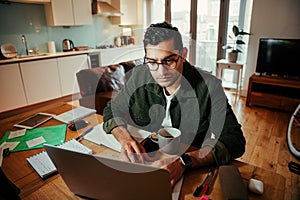 Mixed race businessman working on laptop sitting at home office