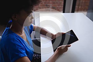 Mixed race businesswoman sitting in office using tablet with blank screen