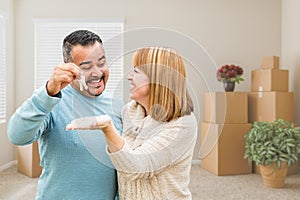 Mixed Race Couple Holding House Keys Inside Empty Room with Moving Boxes