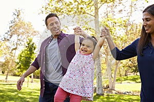 Mixed race couple lifting young daughter in park, close up