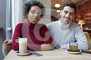 Mixed race couple listeting to interisting story of their friend in cozy cafe