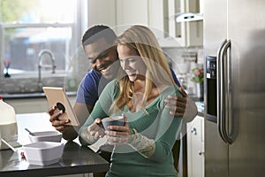 Mixed race couple looking at a tablet computer together in kitchen