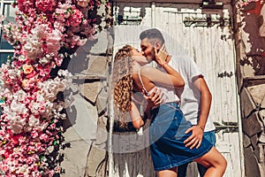Mixed race couple in love hugging and kissing by door outdoors. Arab man and white woman walking in city.