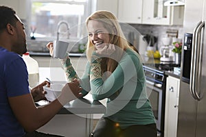 Mixed race couple talking in the kitchen, woman laughing