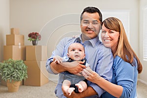 Mixed Race Family with Baby in Room with Packed Moving Boxes