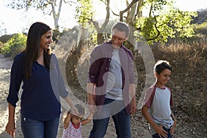 Mixed race family walking on rural path, backlit front view