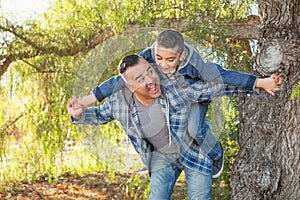 Mixed Race Father And Son Having Fun Piggy Back Outdoors