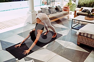 Mixed race female with afro stretching claves while practicing downward dog pose photo