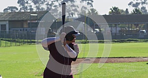 Mixed race female baseball player, hitter, swinging bat for pitched ball