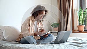 Mixed race female college student having video conference class on laptop.