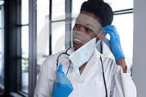 Mixed race female doctor standing putting a face mask on