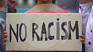 Mixed-race girl holds sign No racism, suffers crowd screaming racial insults