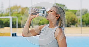 Mixed race hockey player drinking water from a bottle while training. Serious and focused young latino girl taking a