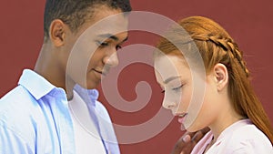 Mixed-race male teen hesitantly touching shy girl shoulder, first feelings, love