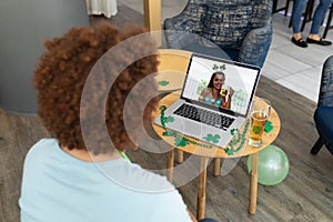 Mixed race man at bar making st patrick\'s day video call to friend on laptop