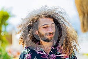 mixed race man with curly long hair outdoors ar sunny day