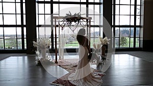 Mixed race modern bride with a wedding bouquet silhouetted against a wedding alter. HD 24FPS.