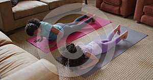 Mixed race mother and daughter practicing yoga in living room