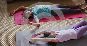 Mixed race mother and daughter practicing yoga in living room