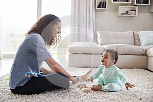 Mixed race mum and toddler son playing in sitting room