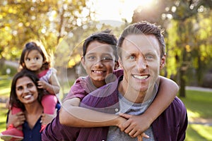 Mixed race parents carry kids piggyback, selective focus photo