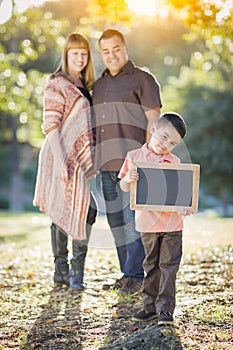 Mixed Race Parents Standing Behind Son with Blank Chalk Board